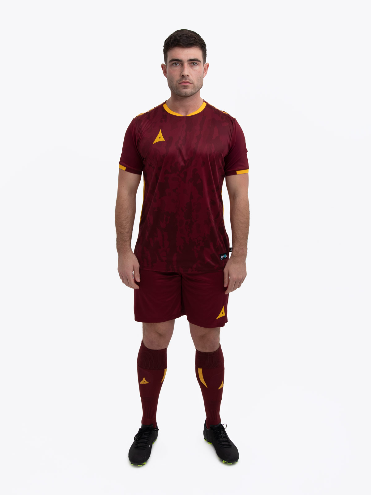 a model standing up wearing a claret and amber football shirt, shorts and football socks.
